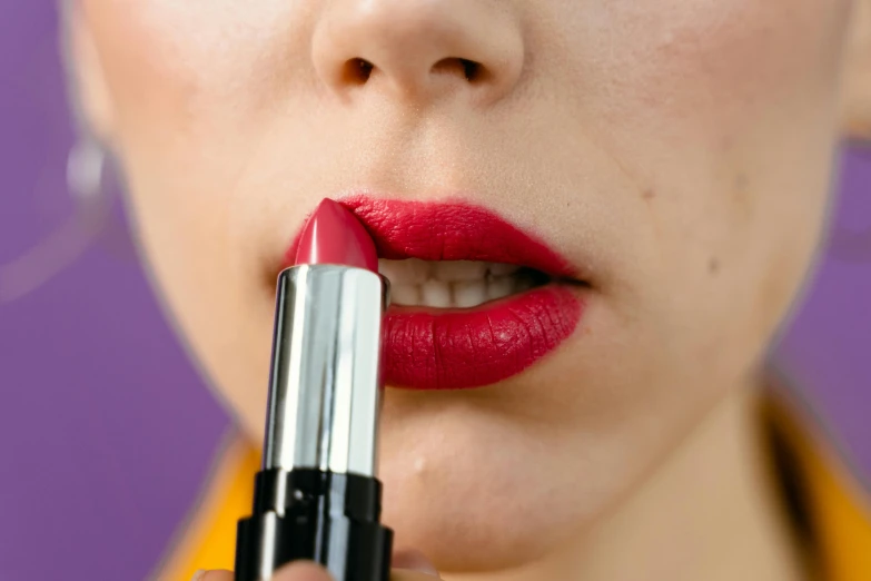 a girl taking the lipstick out and showing off her red lips