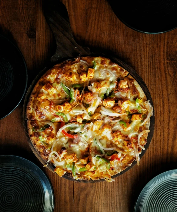 a pizza with vegetables and cheese is sitting on a wood table