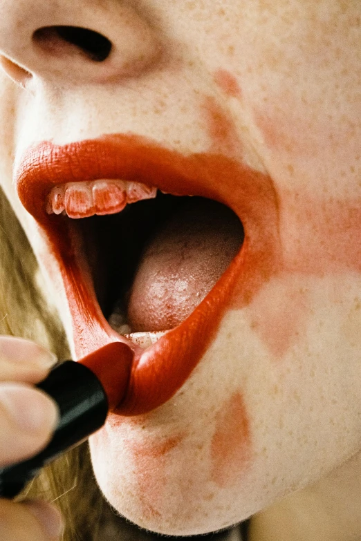 a woman wearing a wet red lip brushes her nose