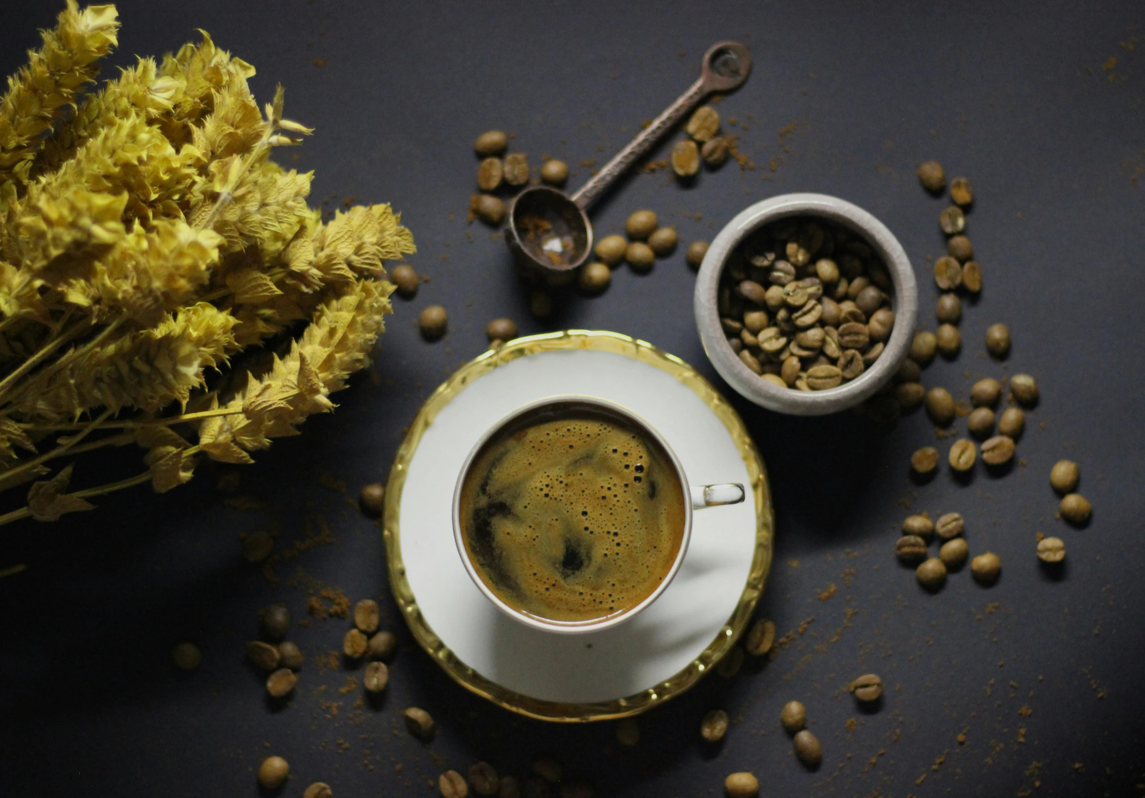 the cup of coffee is on the saucer next to it with mustard seeds