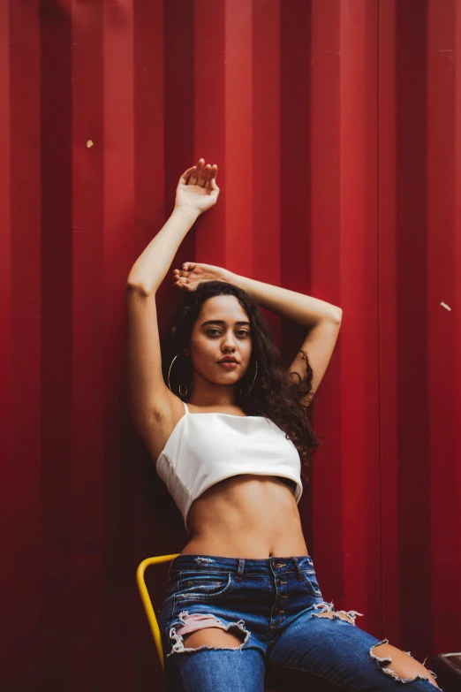 a woman sitting on a yellow chair next to red wall