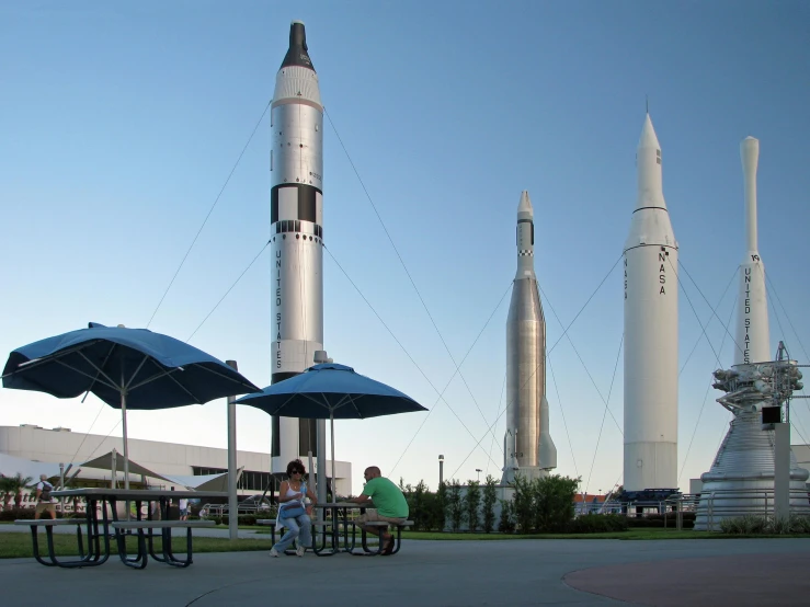 people sitting around a picnic area with rockets in the background