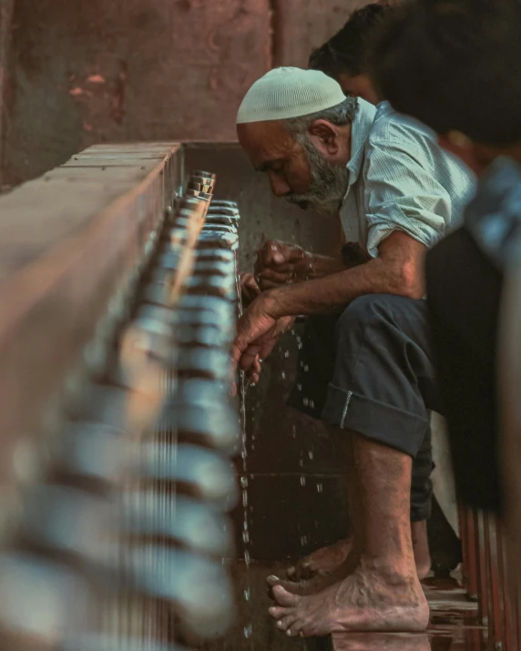 a man in traditional clothing is washing his hands with water