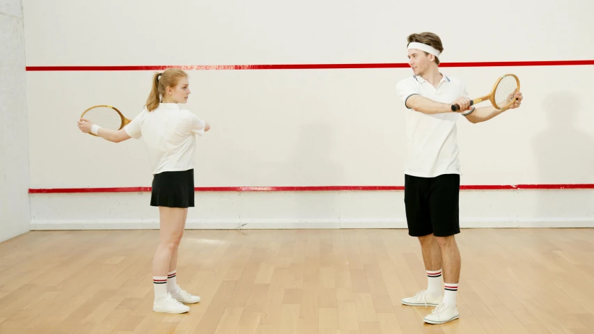 two people standing together holding tennis racquets on the floor