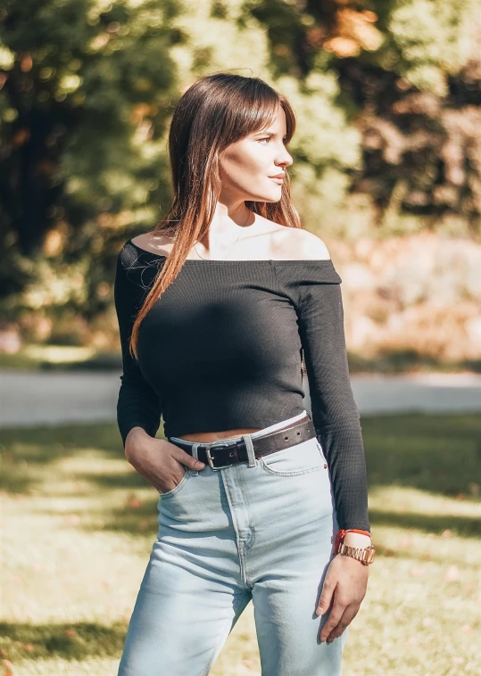 a woman in a black top is posing in a field