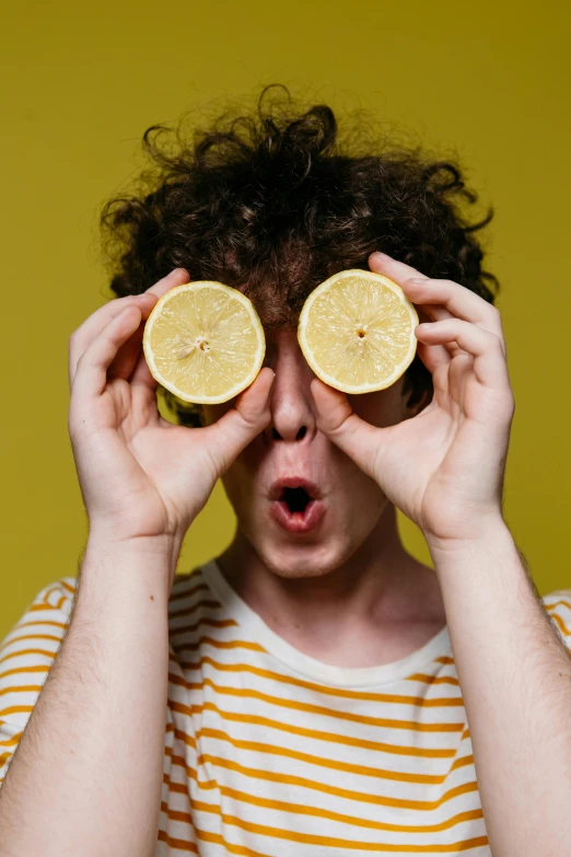 an image of man holding lemons on his eyes