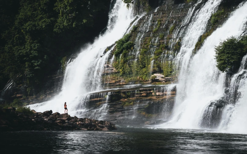 the person is standing near the waterfall while it was raining