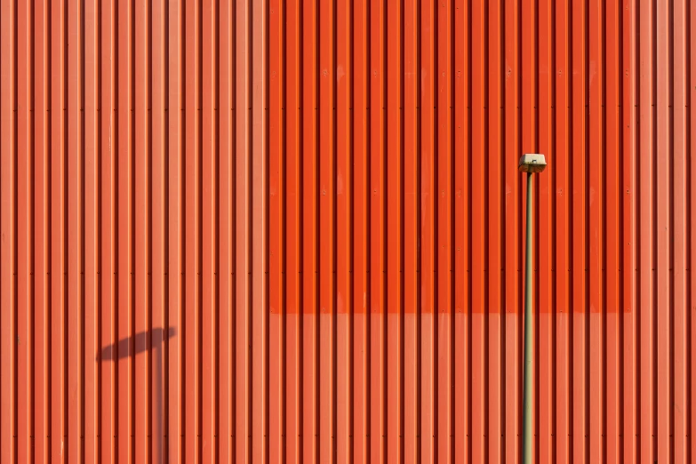 an old rusted red building has a tall lamp post