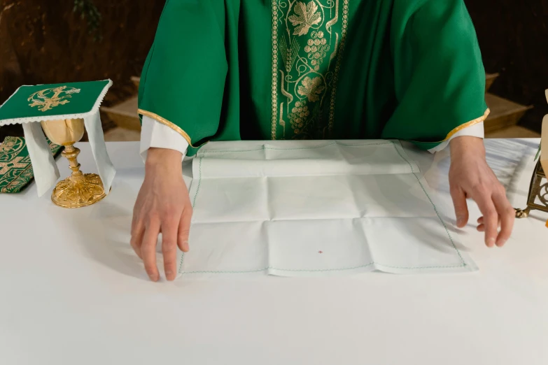 the hands of a woman in priest robes next to small objects