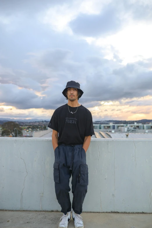 a man in a hat is leaning against a wall