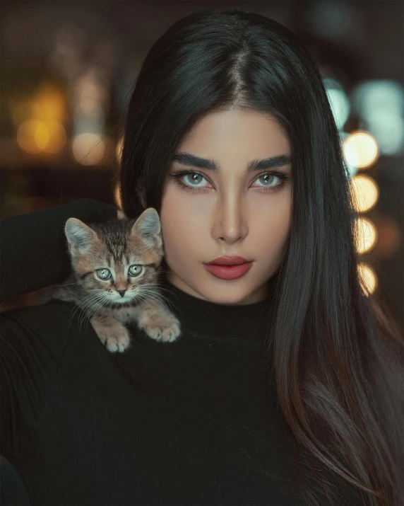 a woman holding a kitten on her shoulder