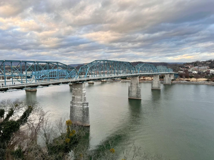 blue iron bridge spanning across a river in an island area