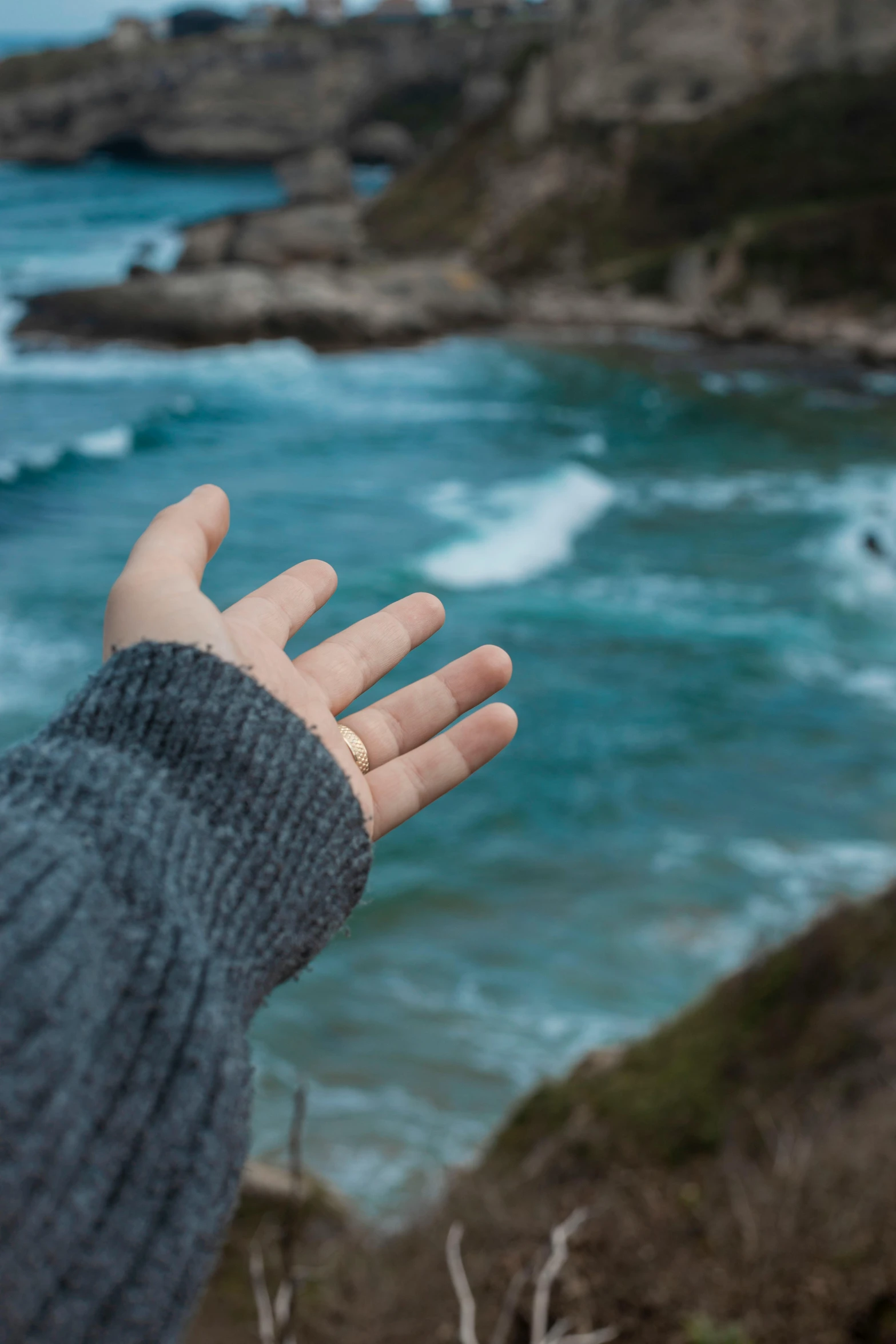 hand extending toward the ocean next to water