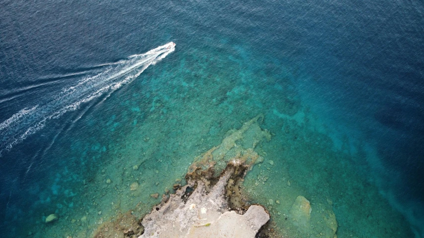 an aerial view of two boats on blue water