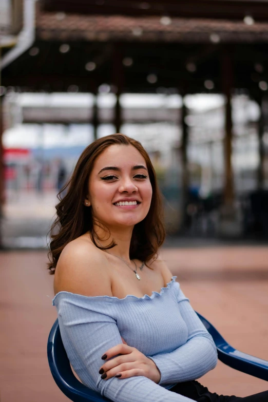 a pretty young lady sitting on a blue chair