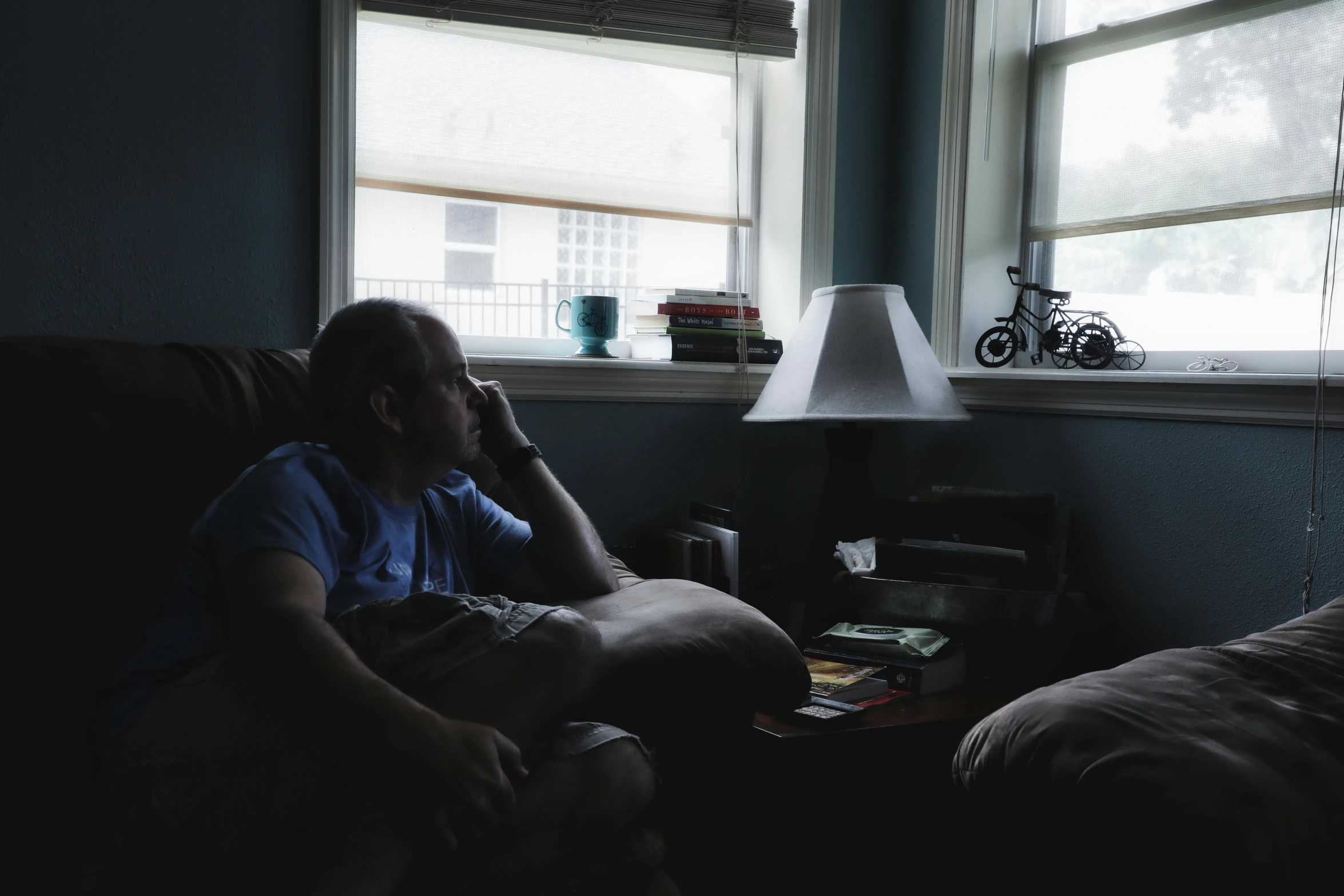 man in the dark talking on his phone next to a window