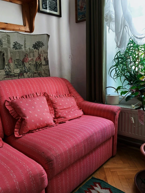 a pink couch sitting in front of a window