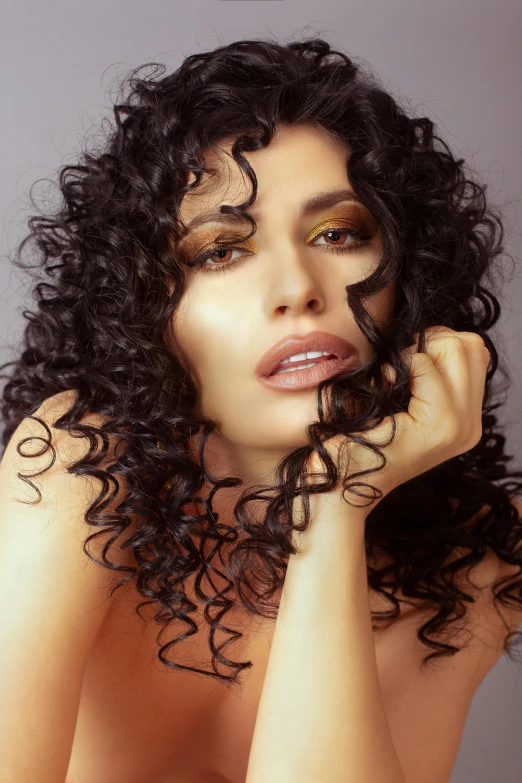  woman with curly hair and makeup posing for camera