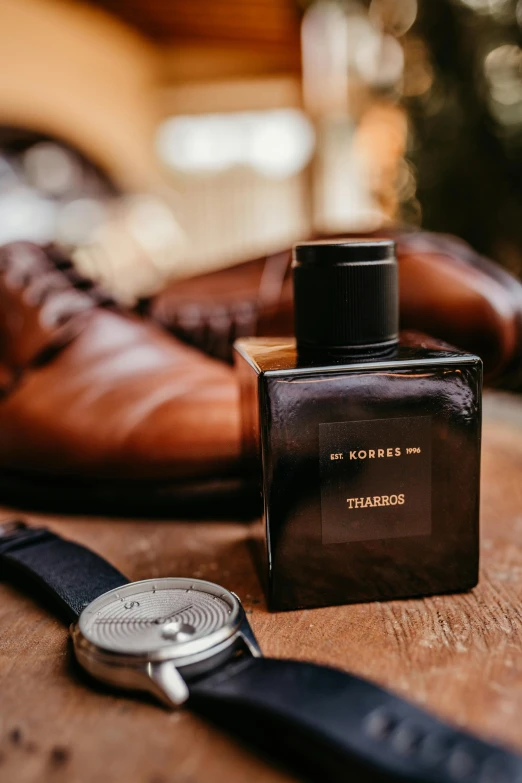 an old fashion watch on top of a wooden table next to a bottle of alcohol