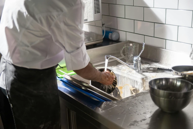 person holding up a bowl and cleaning the sink