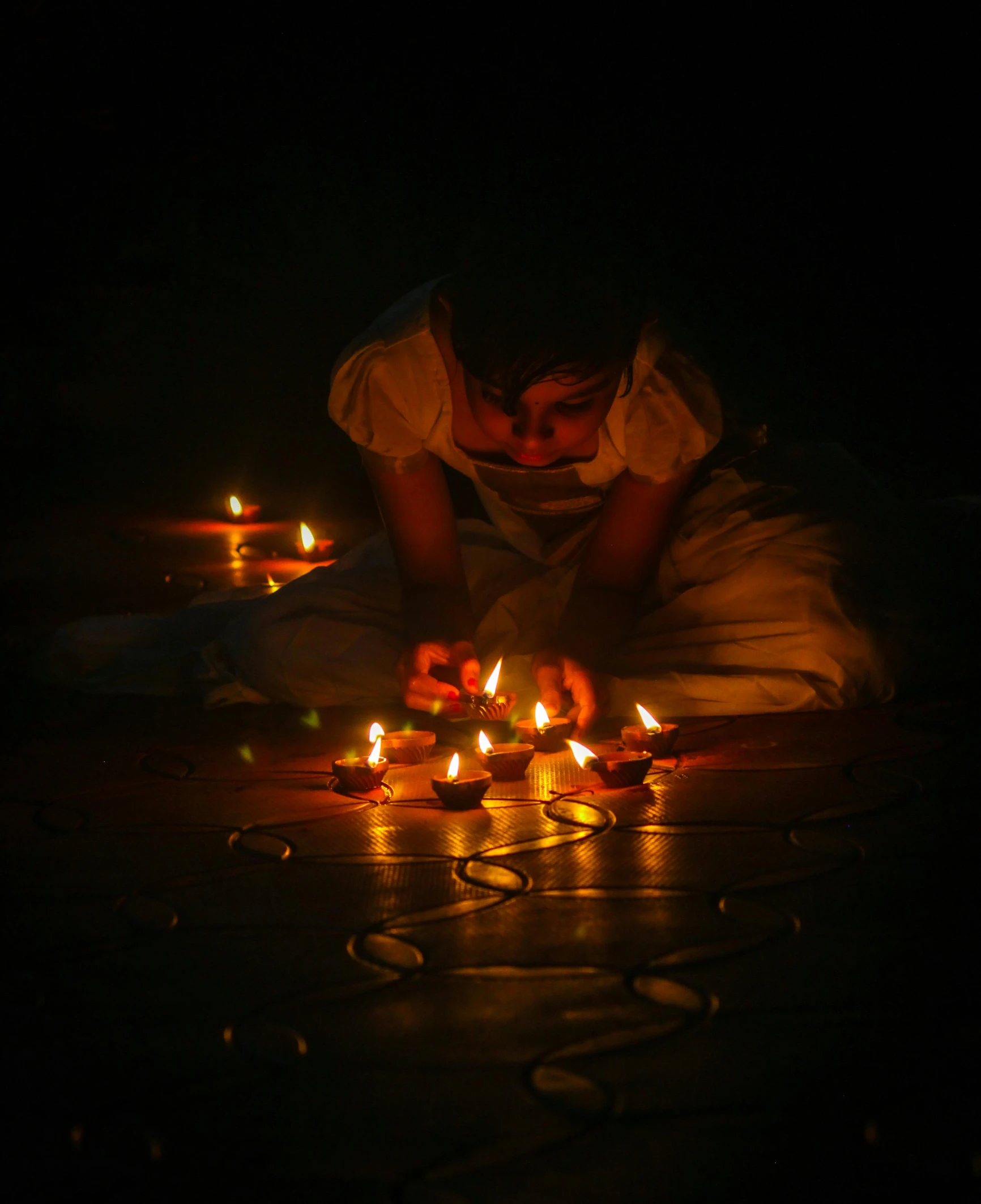 there are candles lit in the dark while two children sit and look at one