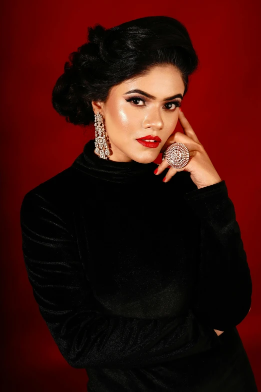 a woman in black dress posing with earrings and ring
