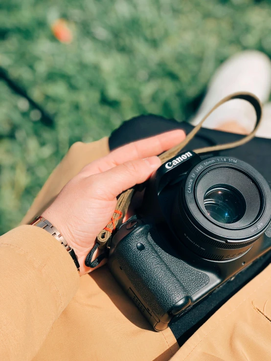 person holding a small compact camera with green grass in background