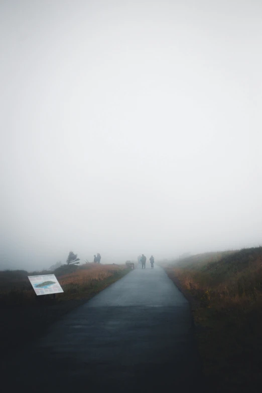 people walking in the distance along a foggy, road