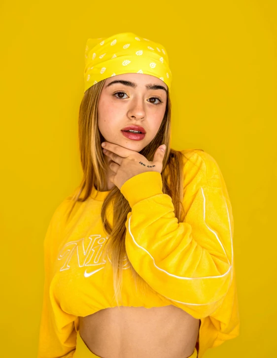 a young woman wearing a yellow crop top and a polka dotted head band