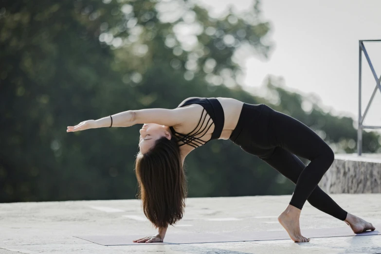a young lady standing on one leg while doing an acrobatic yoga pose