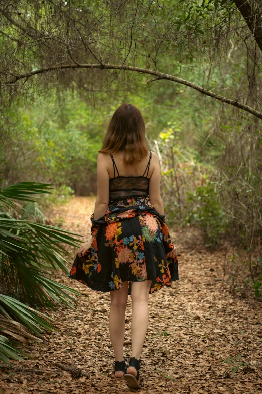 a woman with a colorful dress walking through a forest