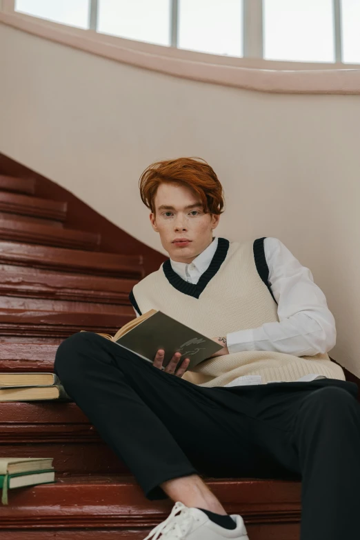 a young man is sitting on the stairs reading a book