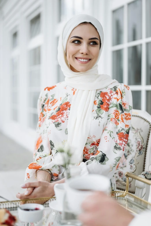 a woman wearing a head scarf standing near a table