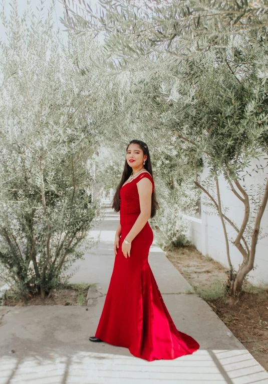 woman in red dress posing on sidewalk under trees