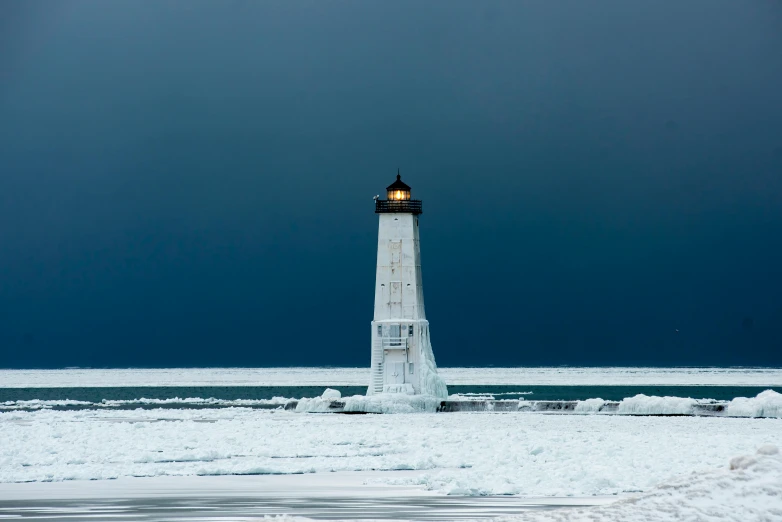 a lighthouse covered in snow on a dark day