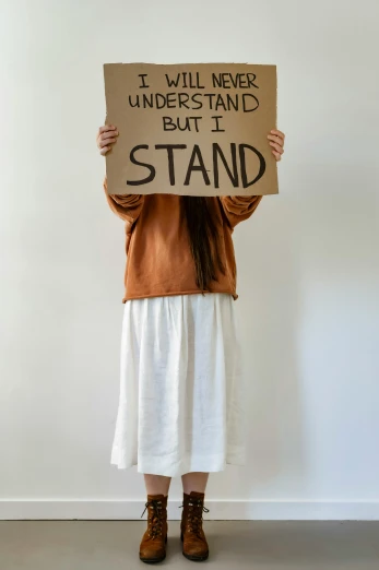 a woman is standing and holding a sign that says i will never understand but i stand