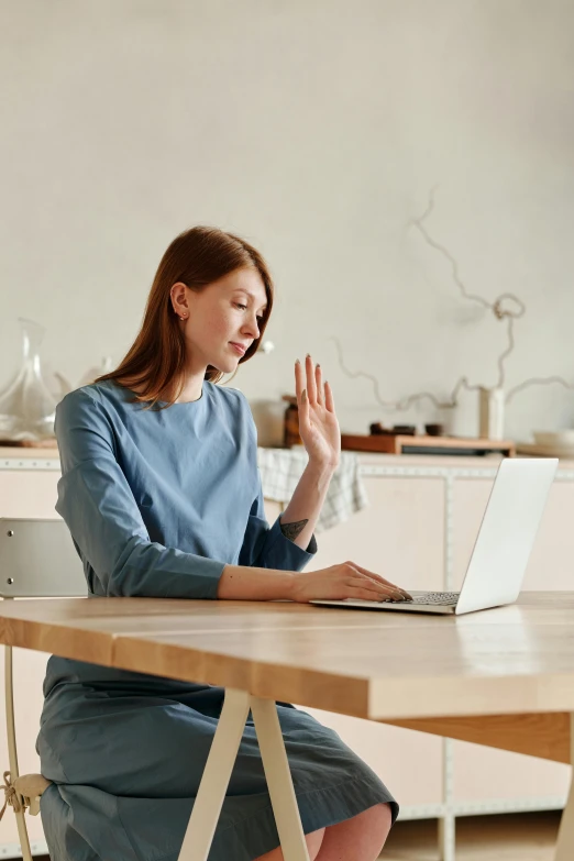 the woman is working at her laptop on the kitchen table