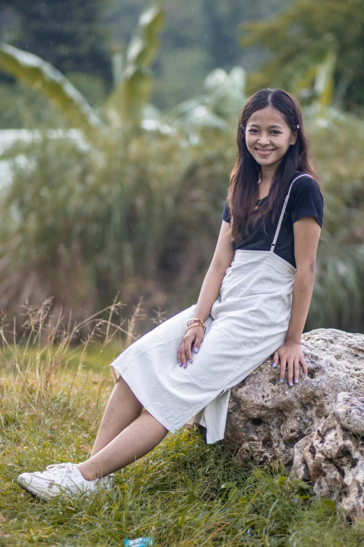 a woman sits on a rock posing for a picture