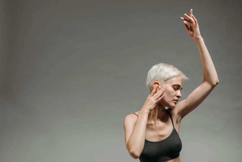 a woman in black underwear stands and holds her arm up