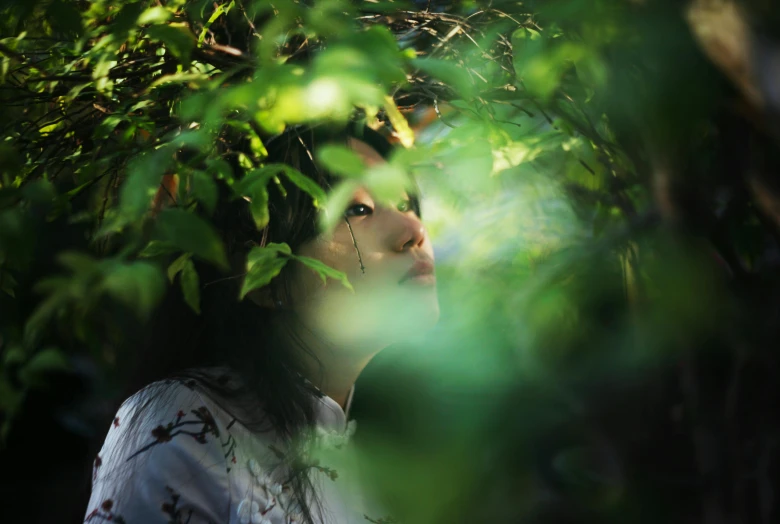 a woman standing in between some leaves