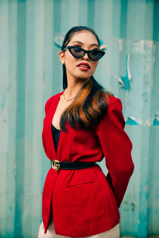 woman standing in front of a corrugated wall wearing black sunglasses