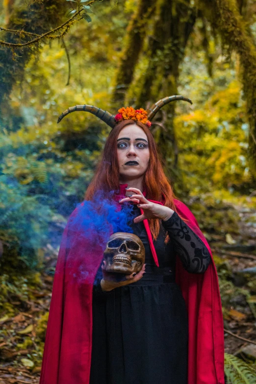 a woman in a red cloak stands in the woods