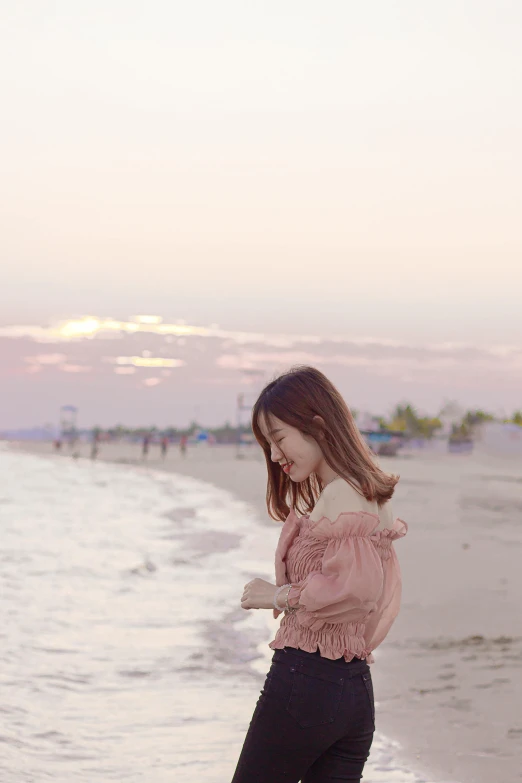 a girl on the beach looking down at her phone