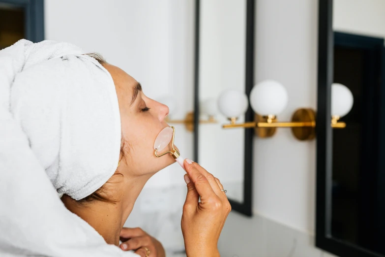 a woman with a towel wrapped around her head brushing her teeth