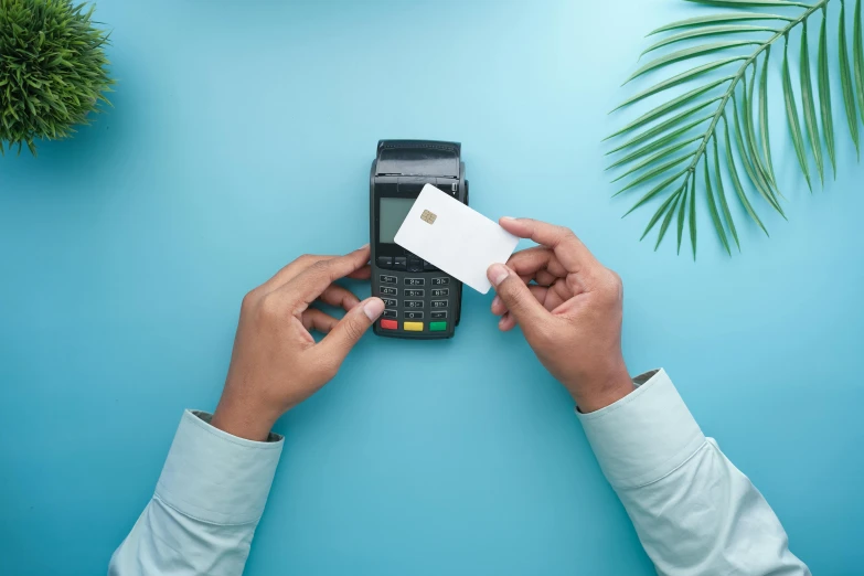 two hands putting a white credit card into a smart phone