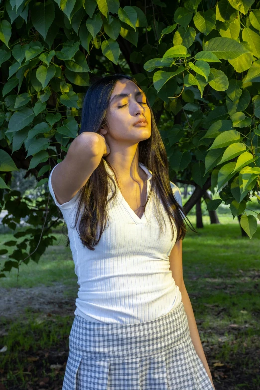 a woman leaning against a tree with her hands on the head