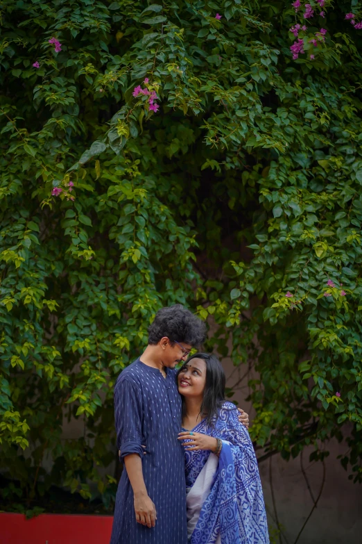 a couple stands in front of some tree nches