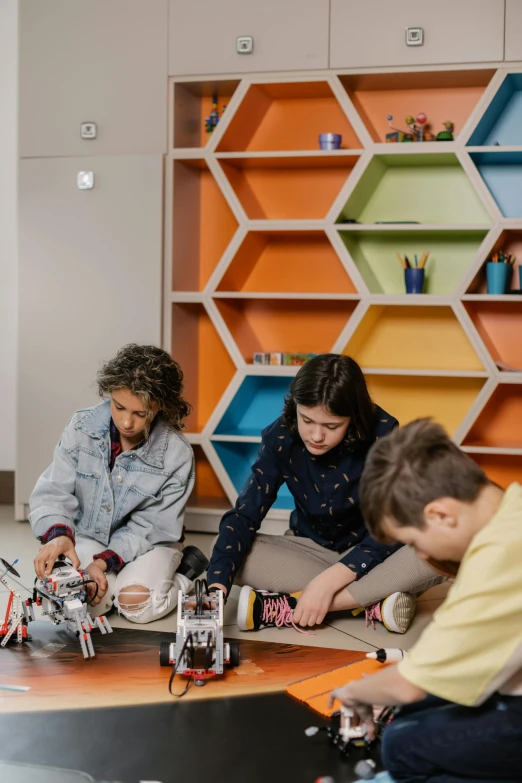 three young adults playing with a toy robot set