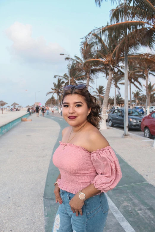 woman with pink off shoulder top standing by the beach