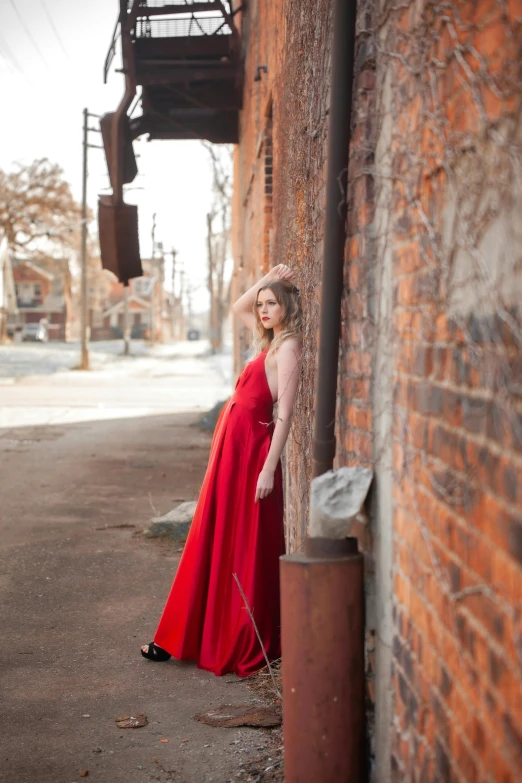 a woman is leaning against a building on the side of a street